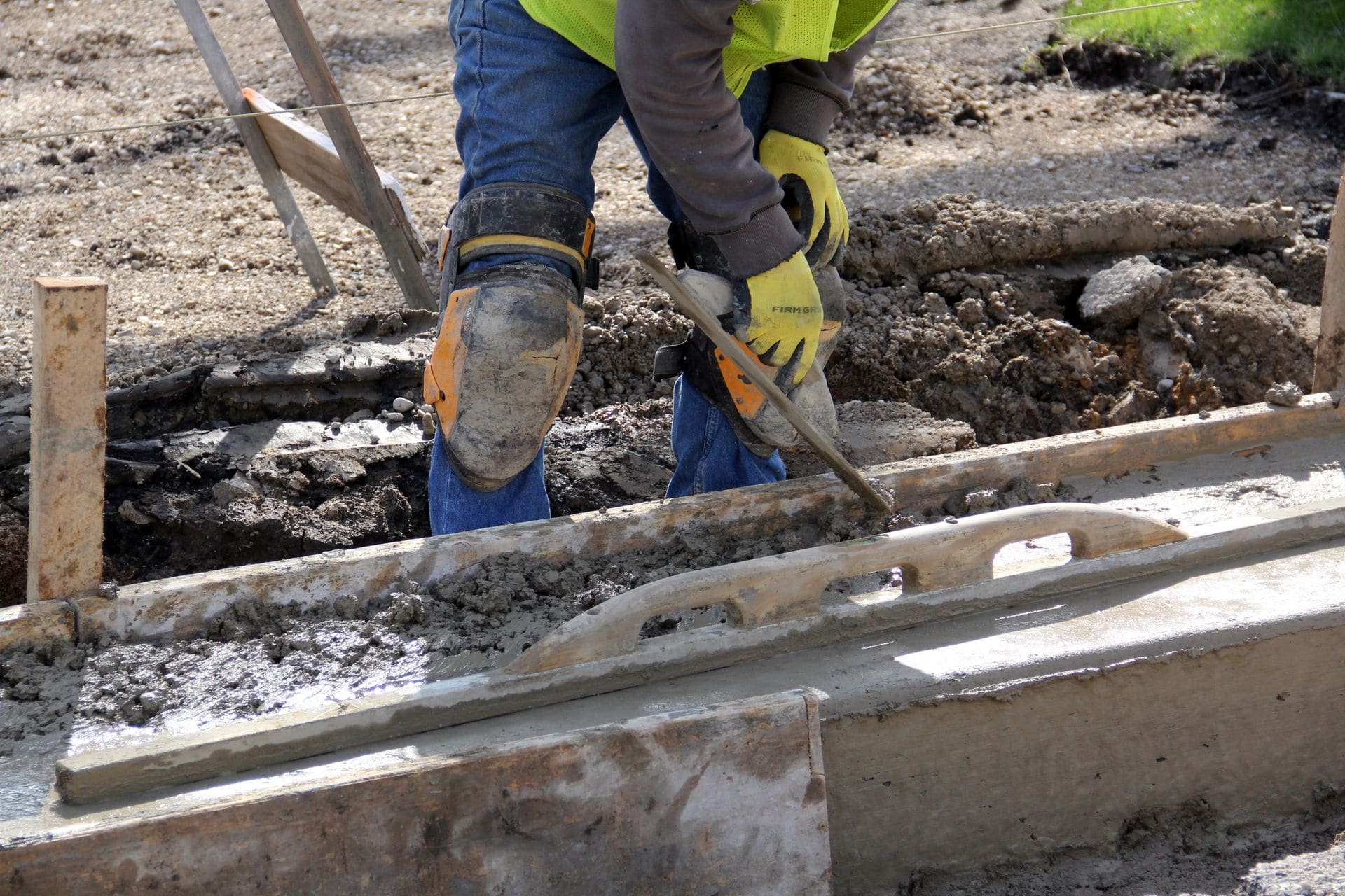 Wet concrete being placed and worked in curb and gutter formwork